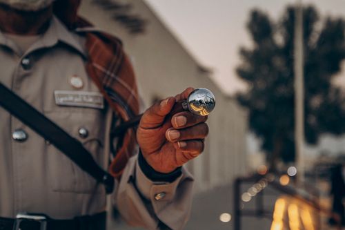 Free An Abu Dhabi police officer in traditional attire holding a reflective object outdoors. Stock Photo