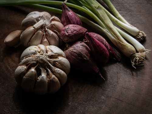 Free Moody still life featuring fresh garlic and onions on wooden table. Stock Photo