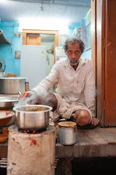 An elderly man prepares food in a traditional kitchen in Varanasi, showcasing cultural culinary practices.