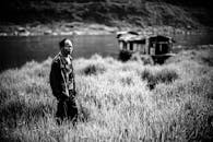 一张黑白照片中，一名男子孤独地开着乡村船在湖边