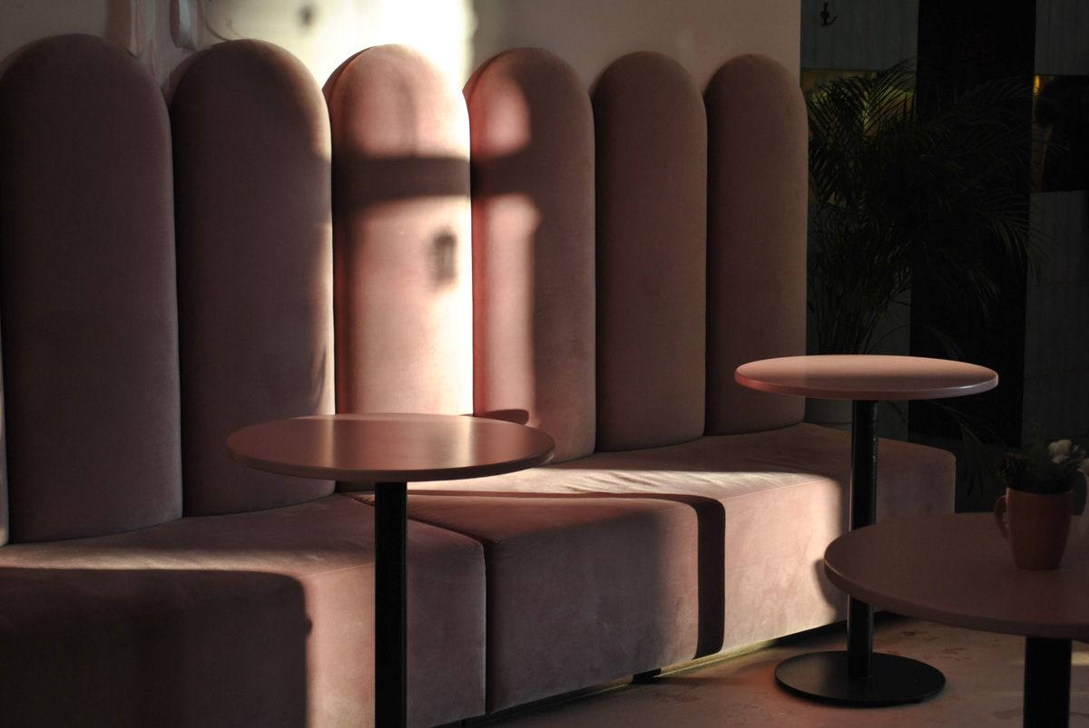 Warm sunlight across pink velvet seating in a modern interior — photo by Valeria Drozdova on Pexels