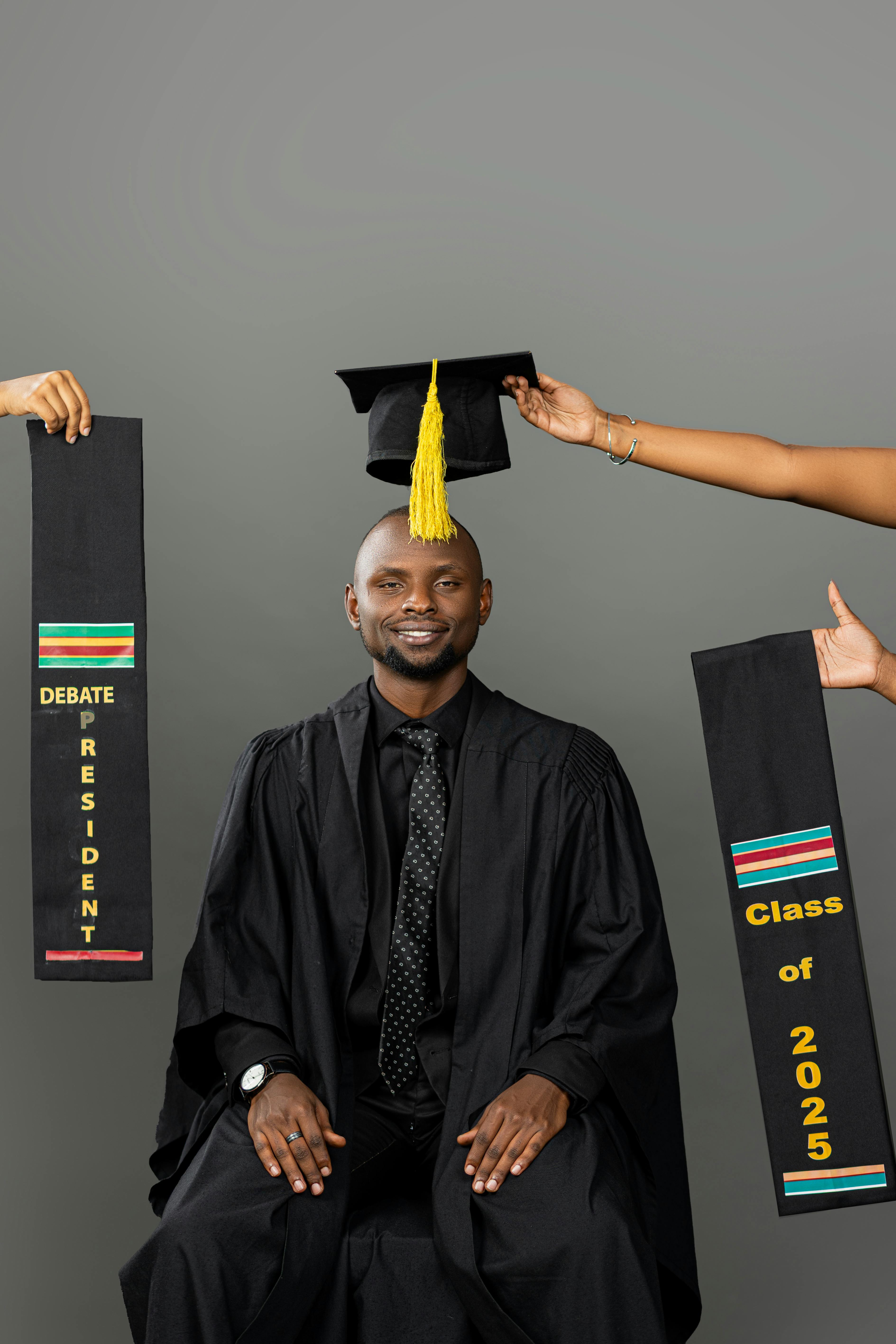 Smiling male graduate in regalia with Class of 2025 banners and cap.