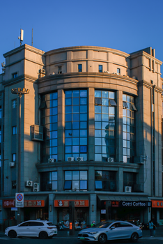 Art Deco style building facade with blue windows and urban features at sunset.