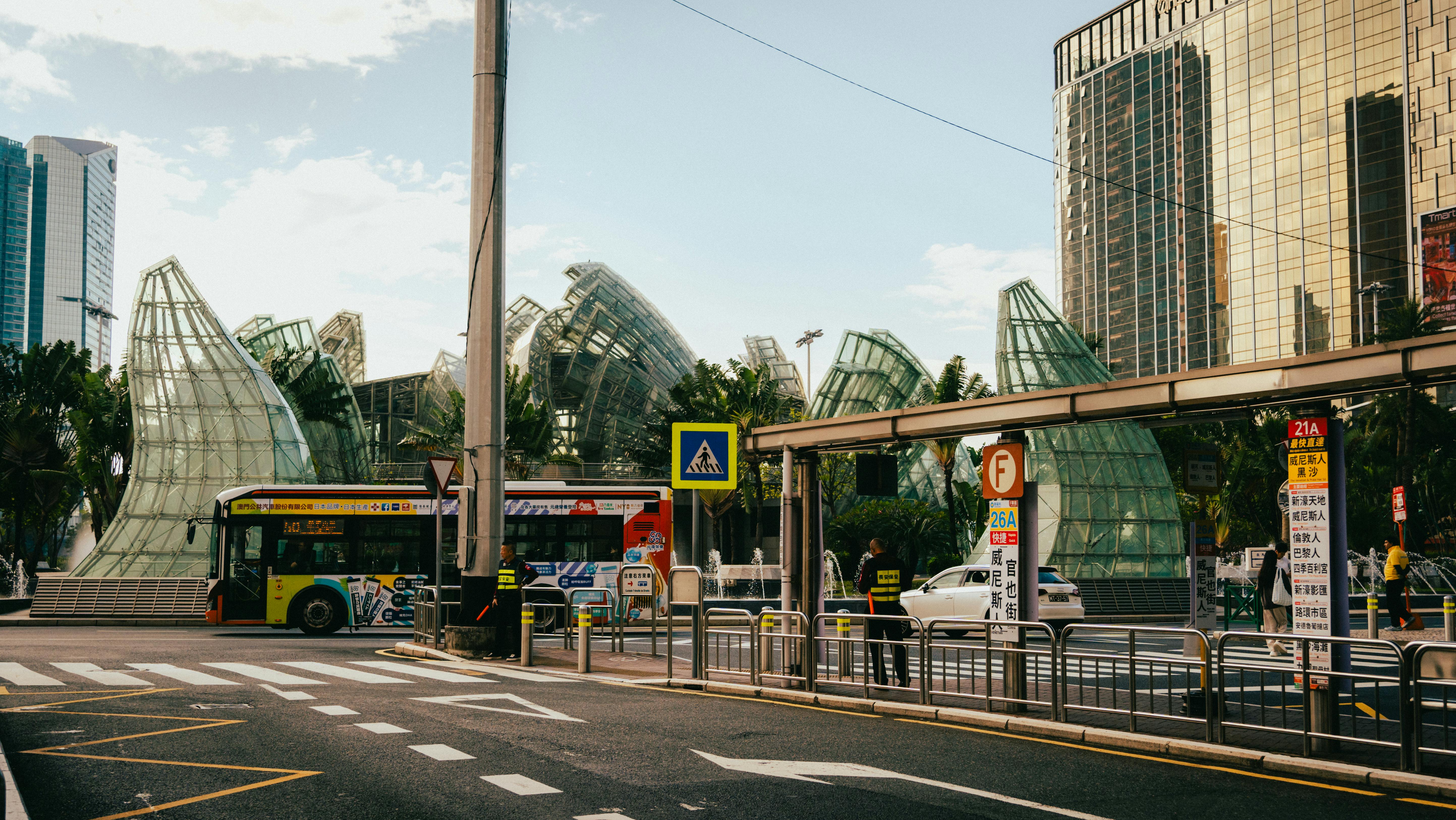 Urban bus stop with modern architecture and city life activity in the backdrop.