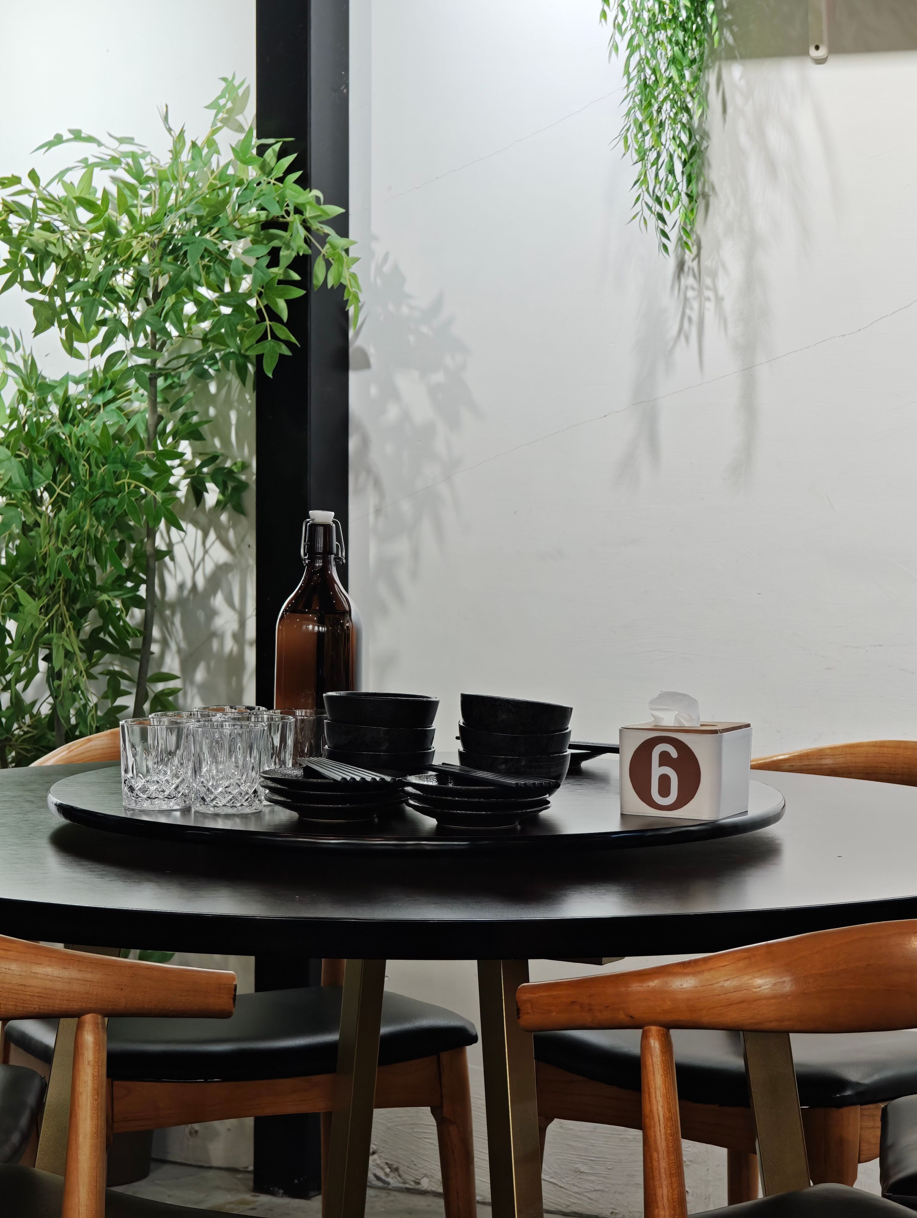 Stylish black table setting with glassware and greenery indoors.