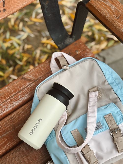 Free Backpack and thermos on a wooden bench with fallen leaves. Stock Photo