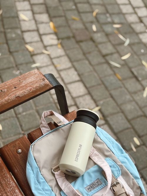 Free Backpack and thermos placed on a park bench, a casual travel setup. Stock Photo