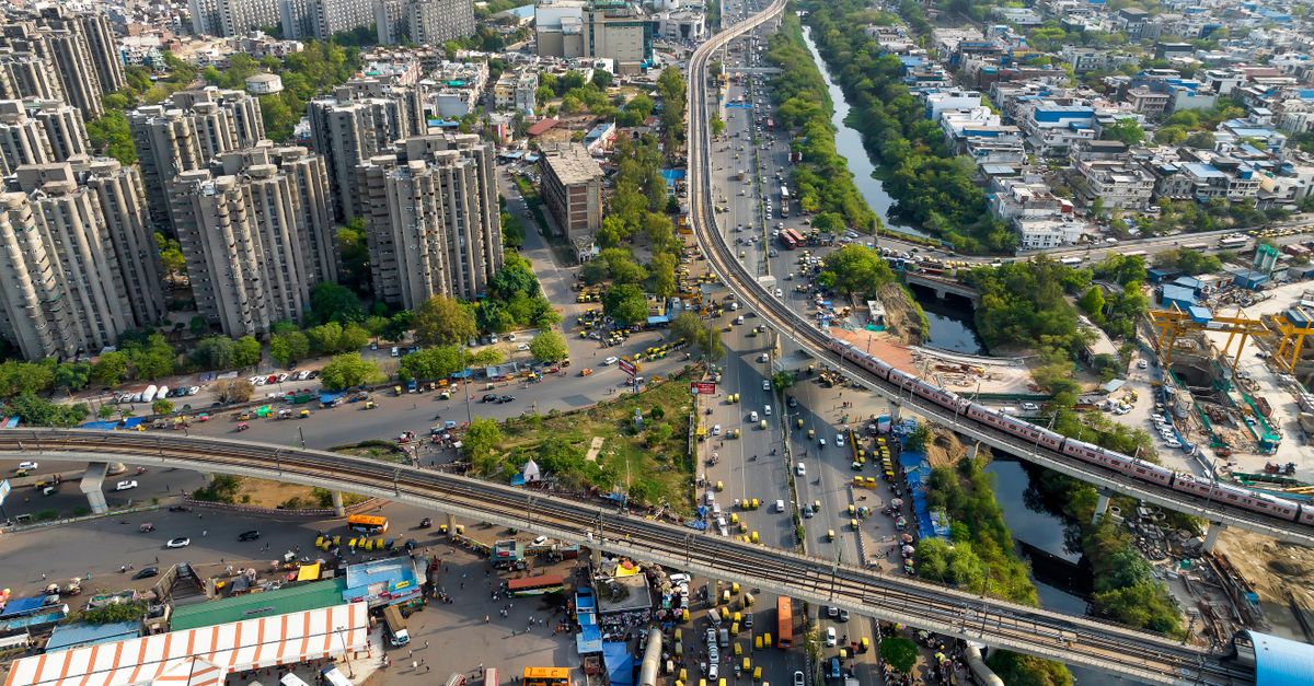 Dynamic aerial view of urban cityscape showing highways, buildings, and greenery.