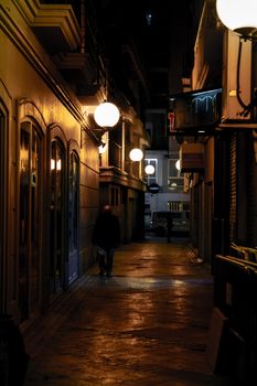 An atmospheric alley scene at night with warm glowing streetlights and a solitary figure walking.