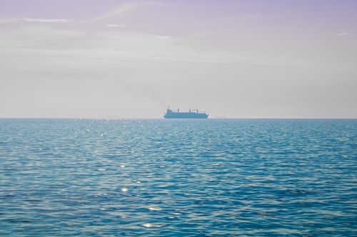 Free A solitary cargo ship sails on calm waters beneath a clear sky, evoking a sense of peace and tranquility. Stock Photo