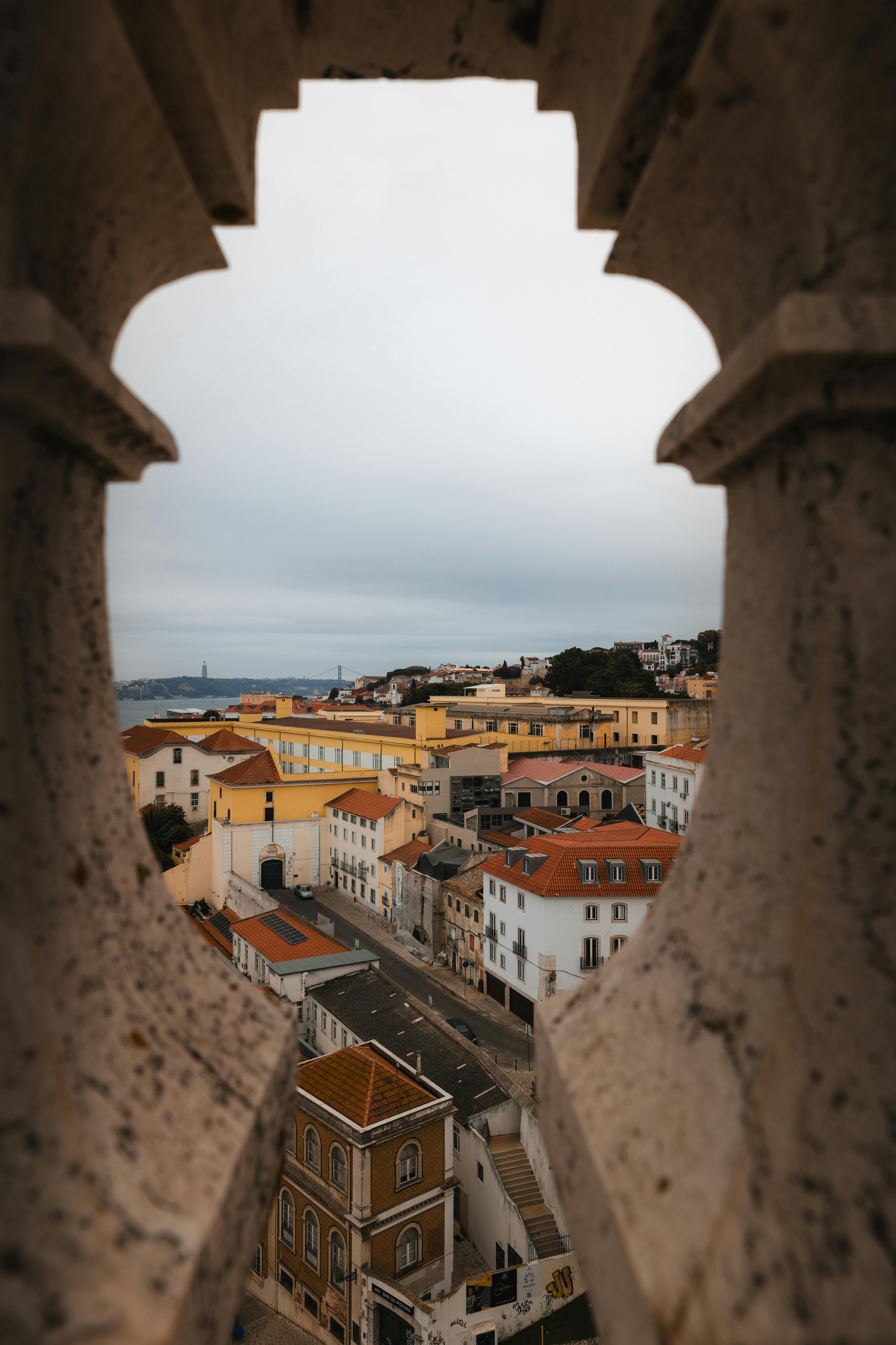 Charming Lisbon cityscape with colorful rooftops viewed through a stone archway, capturing the essence of Portugal.