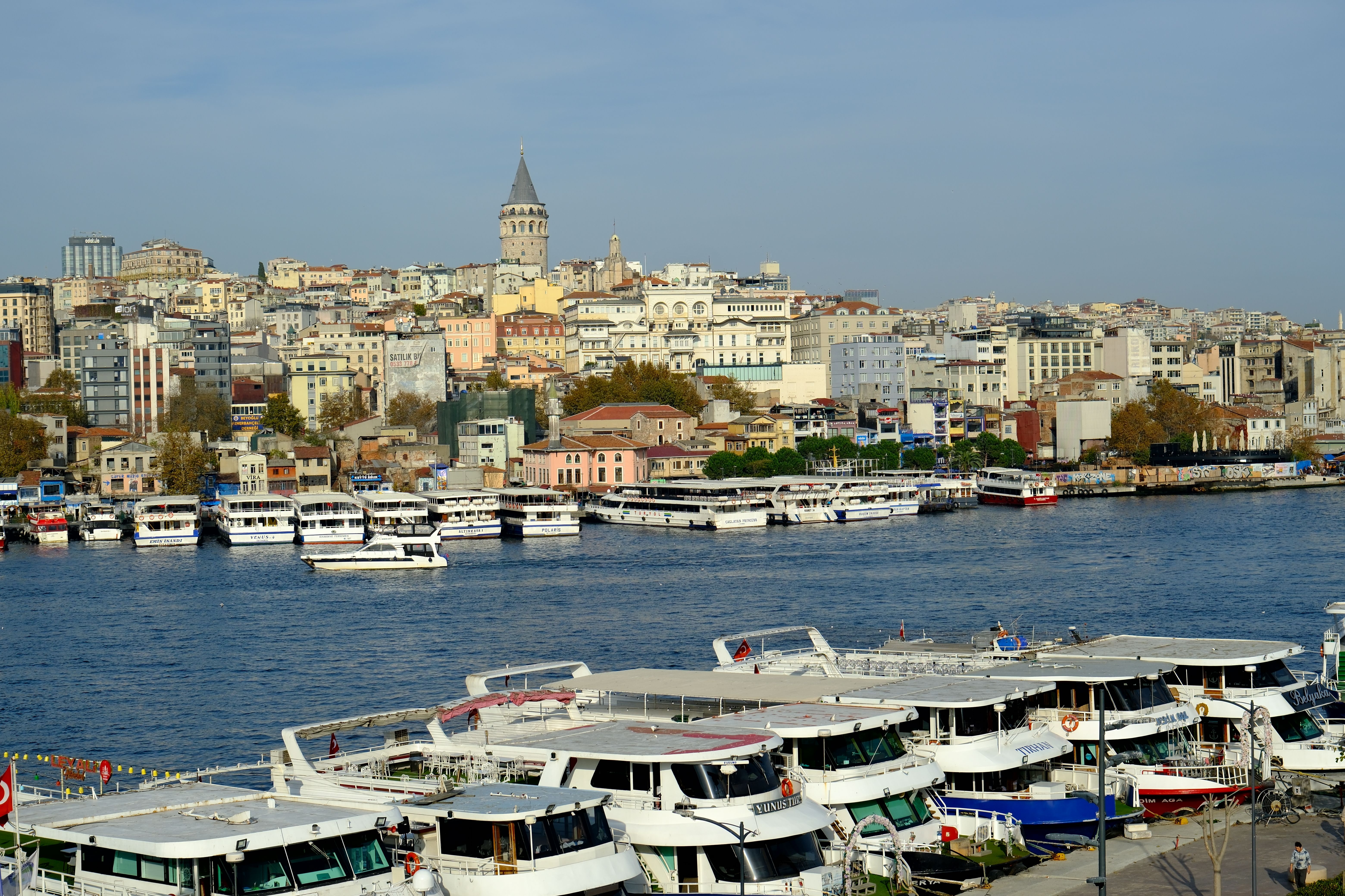 Boats docked near Istanbul's iconic Galata Tower with cityscape backdrop.
