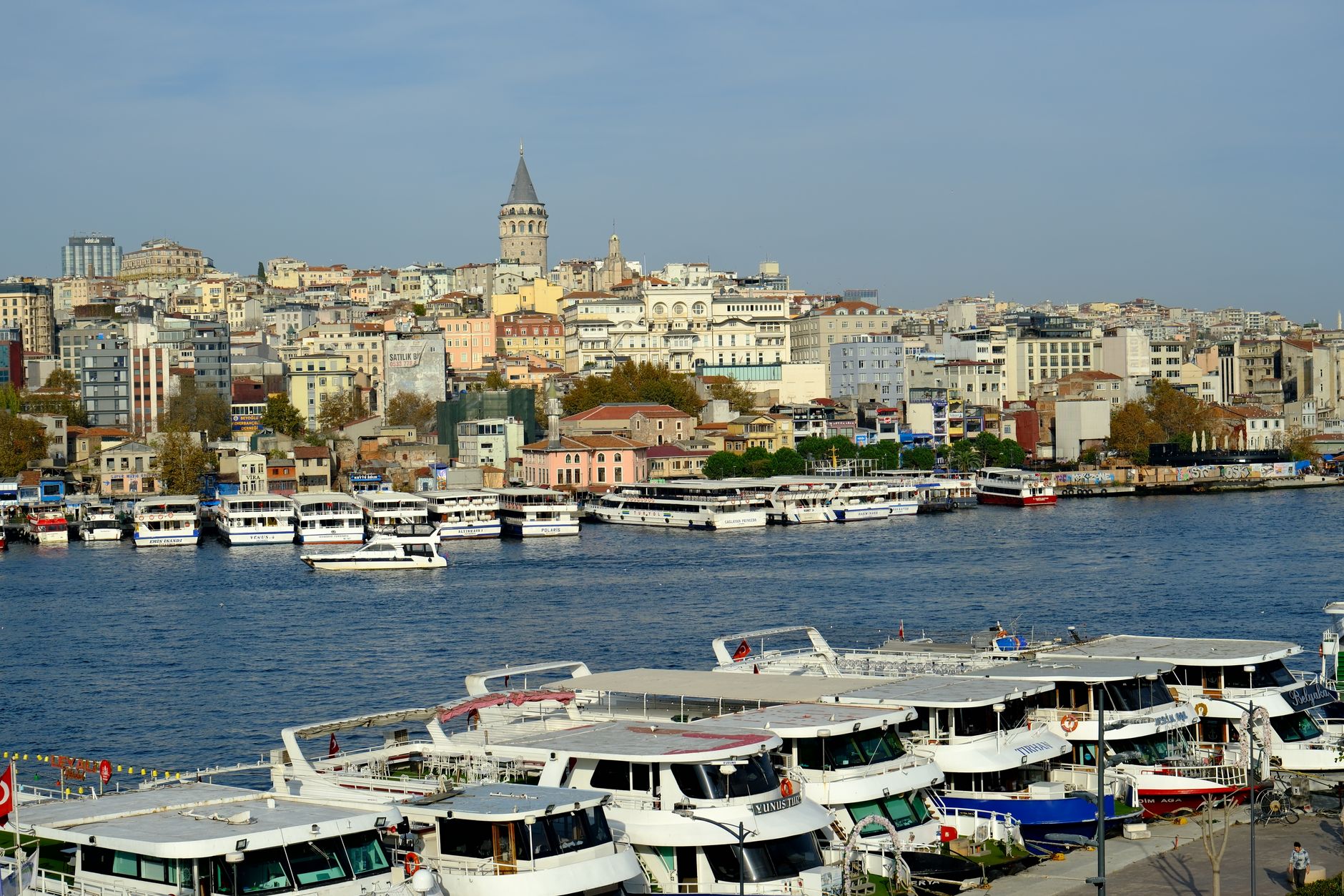 Boats docked near Istanbul's iconic Galata Tower with cityscape backdrop.