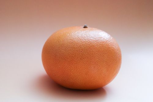 Free Close-up of a fresh grapefruit with a minimalist background, showcasing its vibrant texture. Stock Photo