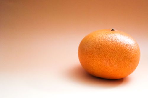 Free A single grapefruit on a warm-toned background, perfect for food or lifestyle content. Stock Photo