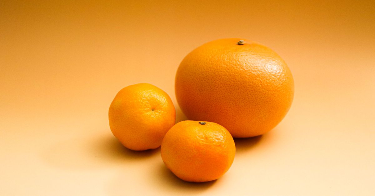 Three citrus fruits including an orange and grapefruit on a gradient orange background. - Evidence evidence guide for grapefruit peel skin health randomized trial