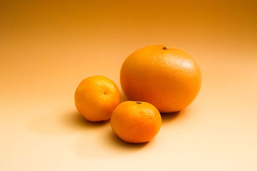 Three citrus fruits including an orange and grapefruit on a gradient orange background.
