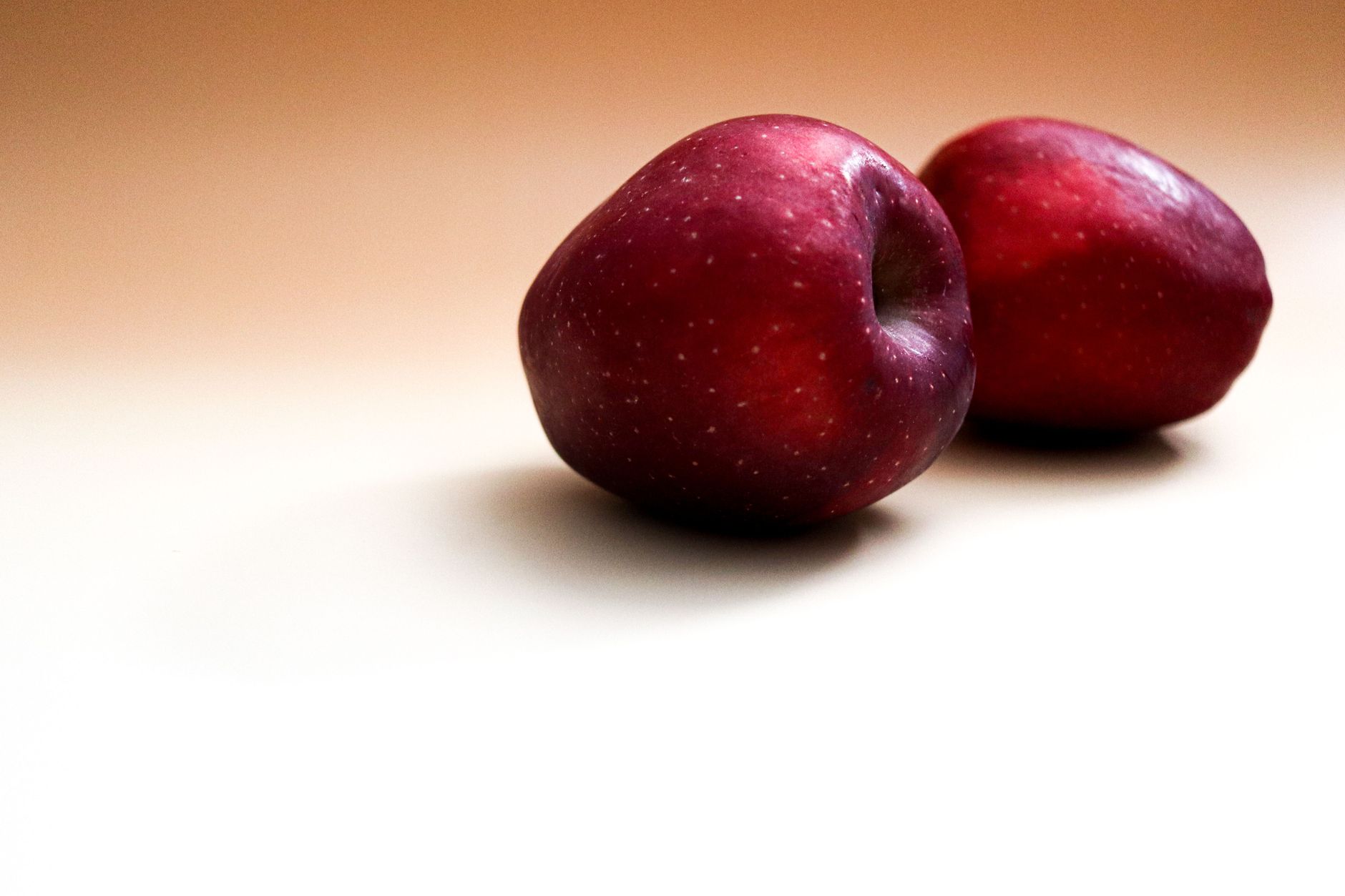 Two fresh red apples on a smooth minimalist background, captured with artistic lighting.