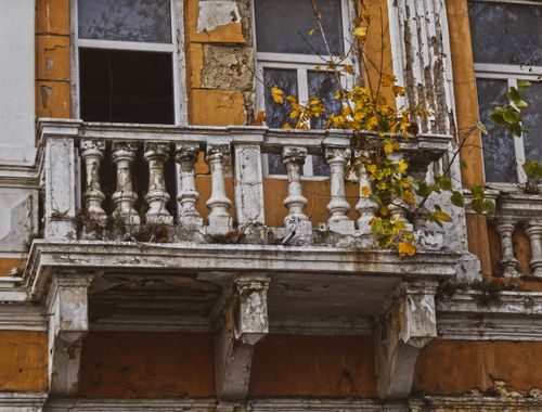Free Close-up of an old balcony with peeling paint and autumn leaves, evoking urban decay and seasonal change. Stock Photo