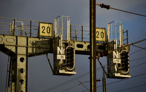 A close-up view of an industrial train signal with lit indicators during dusk, showcasing infrastructure details.