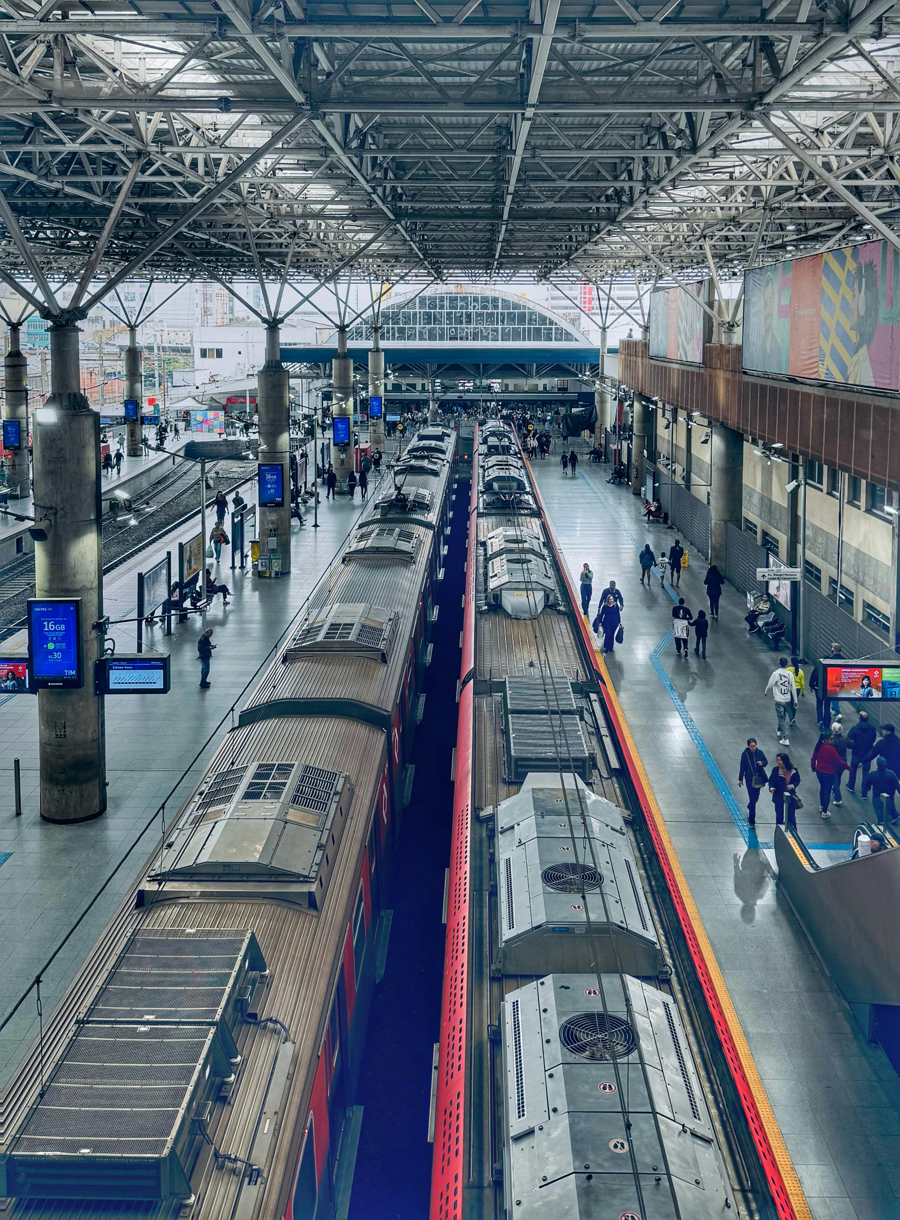 ฟรี สถานีรถไฟที่พลุกพล่านในเซาเปาโล ประเทศบราซิล มีผู้โดยสารและรถไฟหลายขบวนอยู่ใต้หลังคาโลหะ คลังภาพถ่าย