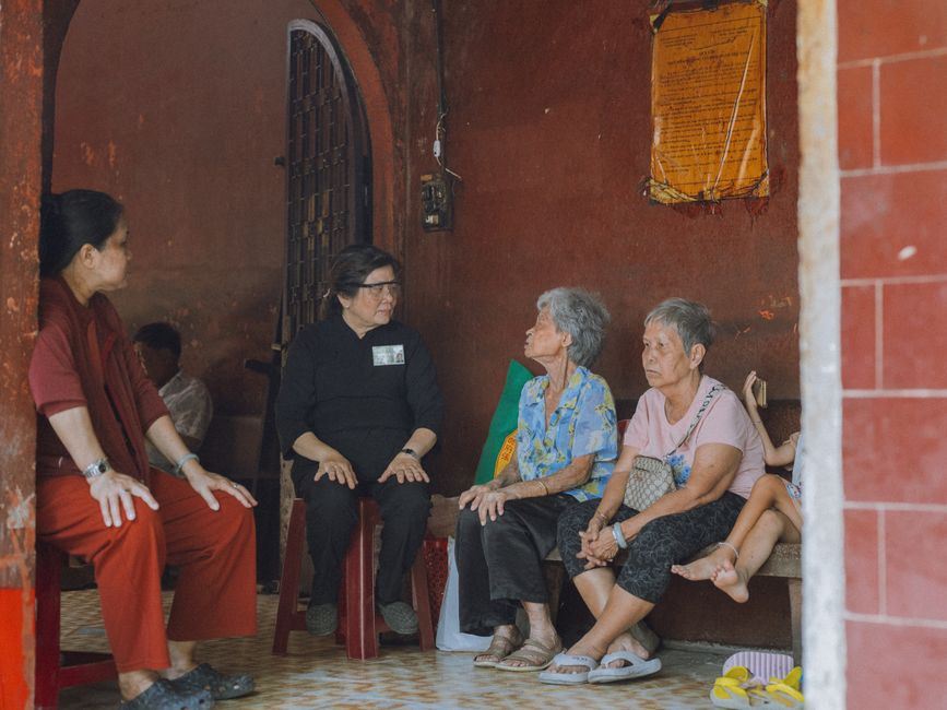A candid scene of elderly women engaging in conversation inside a rustic room, fostering community spirit.