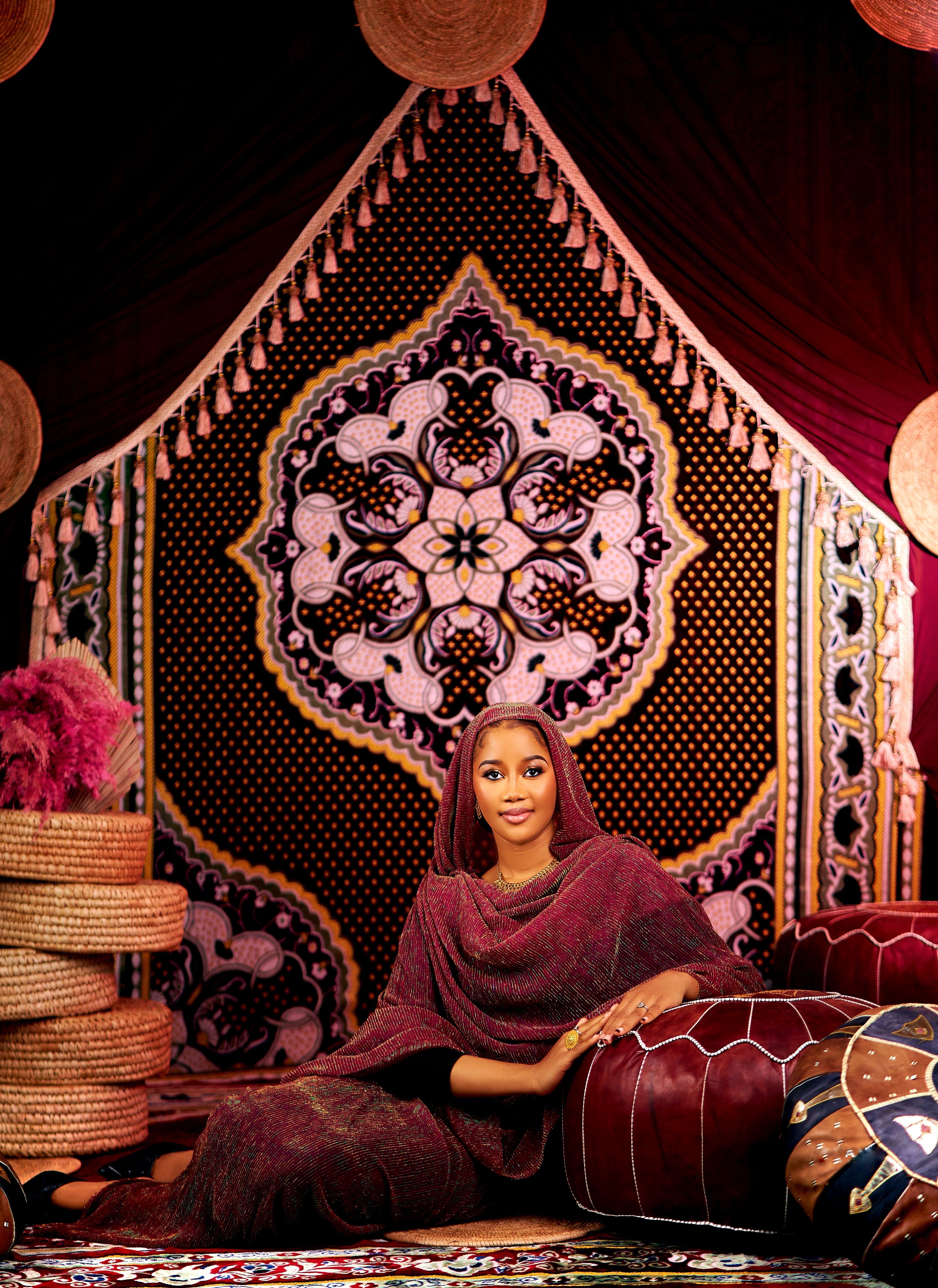 Woman sitting elegantly in vibrant traditional decor, exuding warmth and culture.