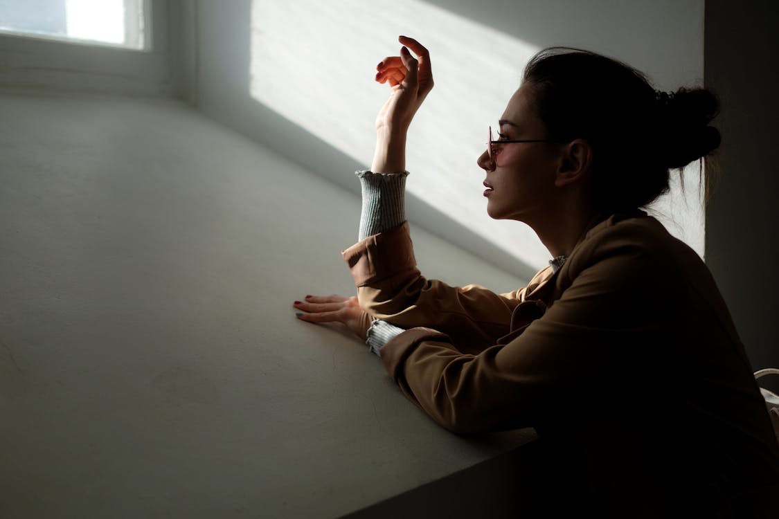 Woman Leaning on White Wall Near Window