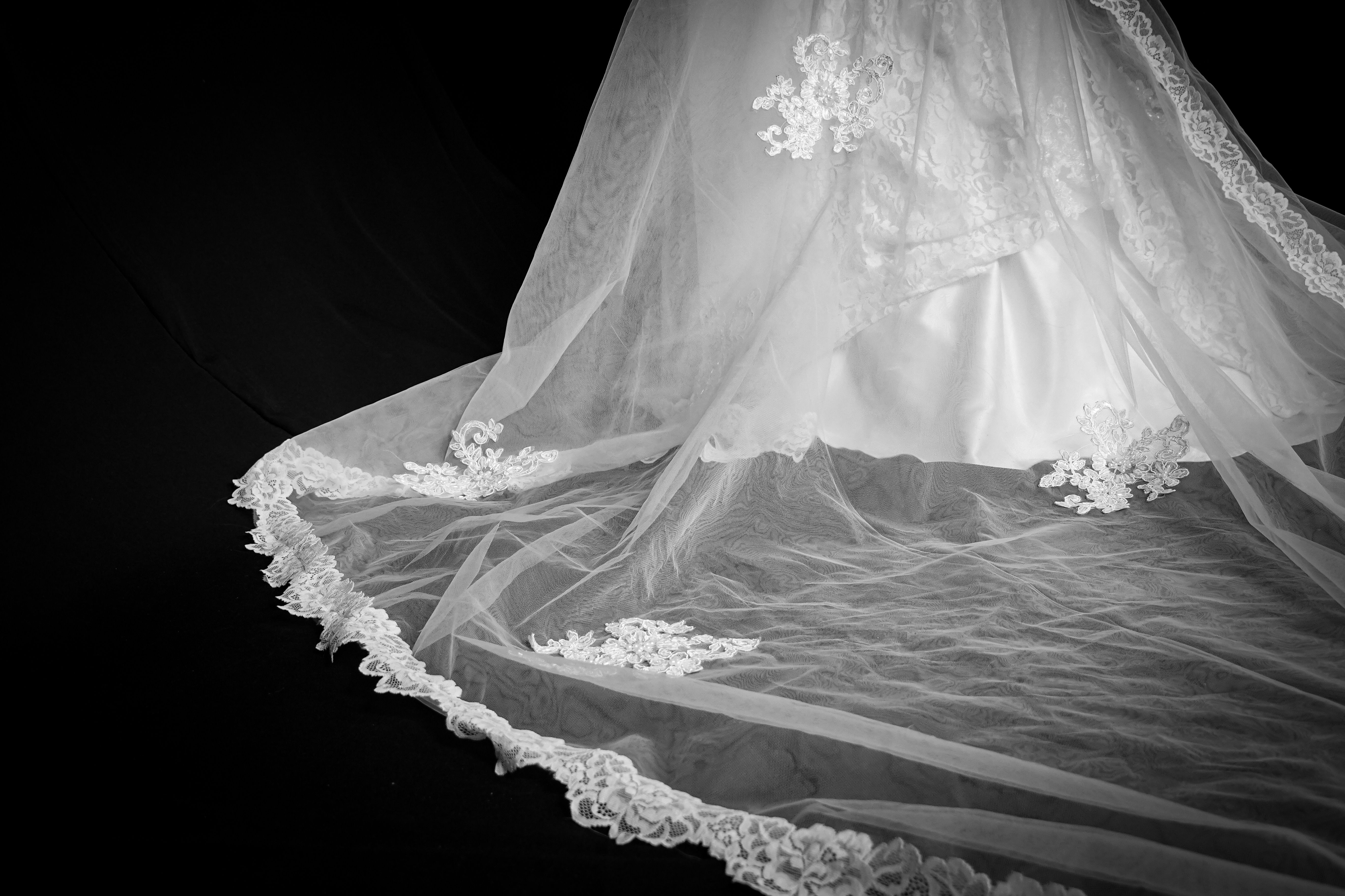 The flowing train of a wedding gown on a wooden studio floor