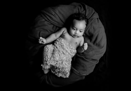 毛布の上に横たわっている赤ちゃんのグレースケール写真