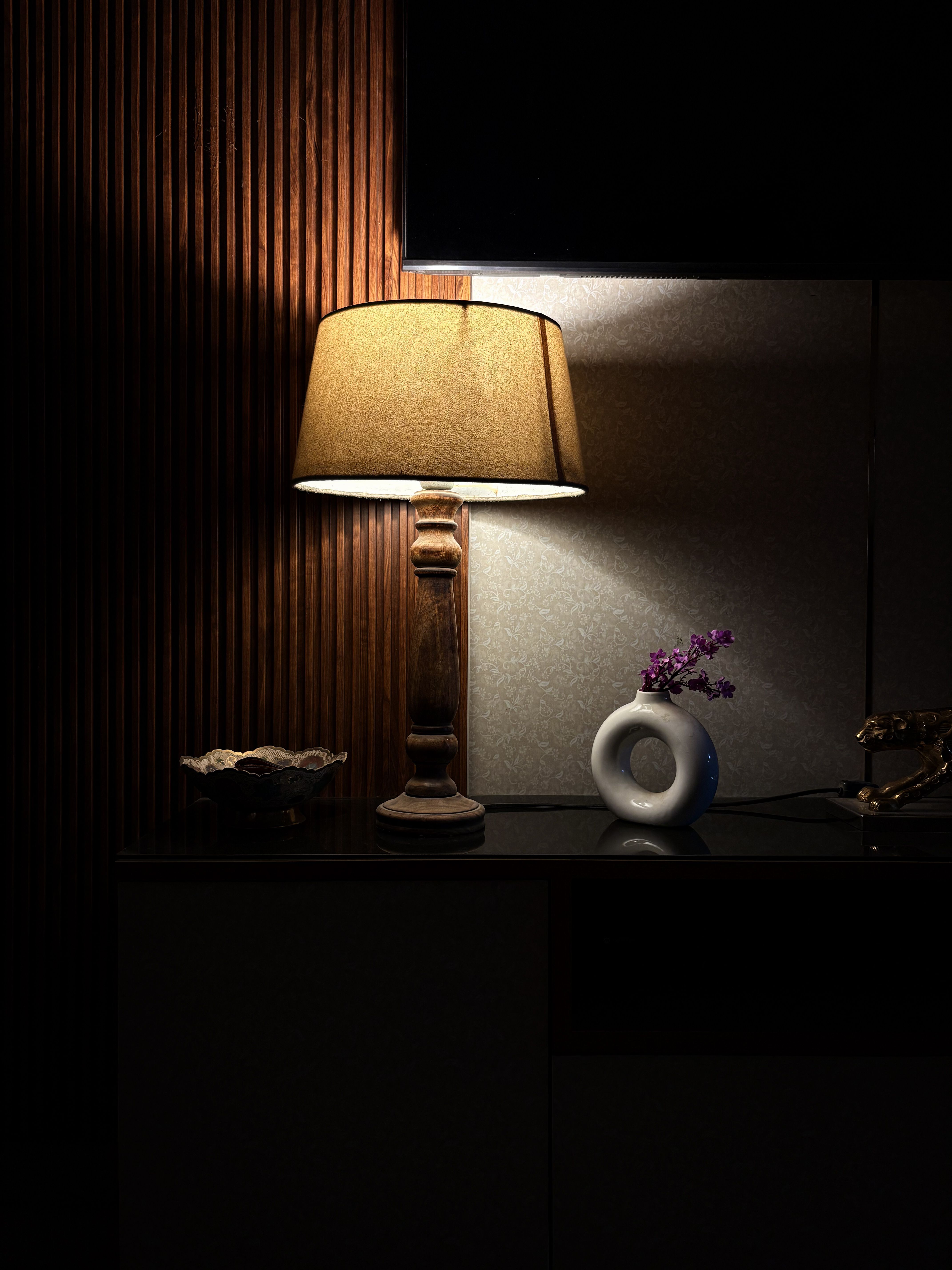 A warm antique lamp illuminates a modern indoor setting with floral decor in Meerut, India.