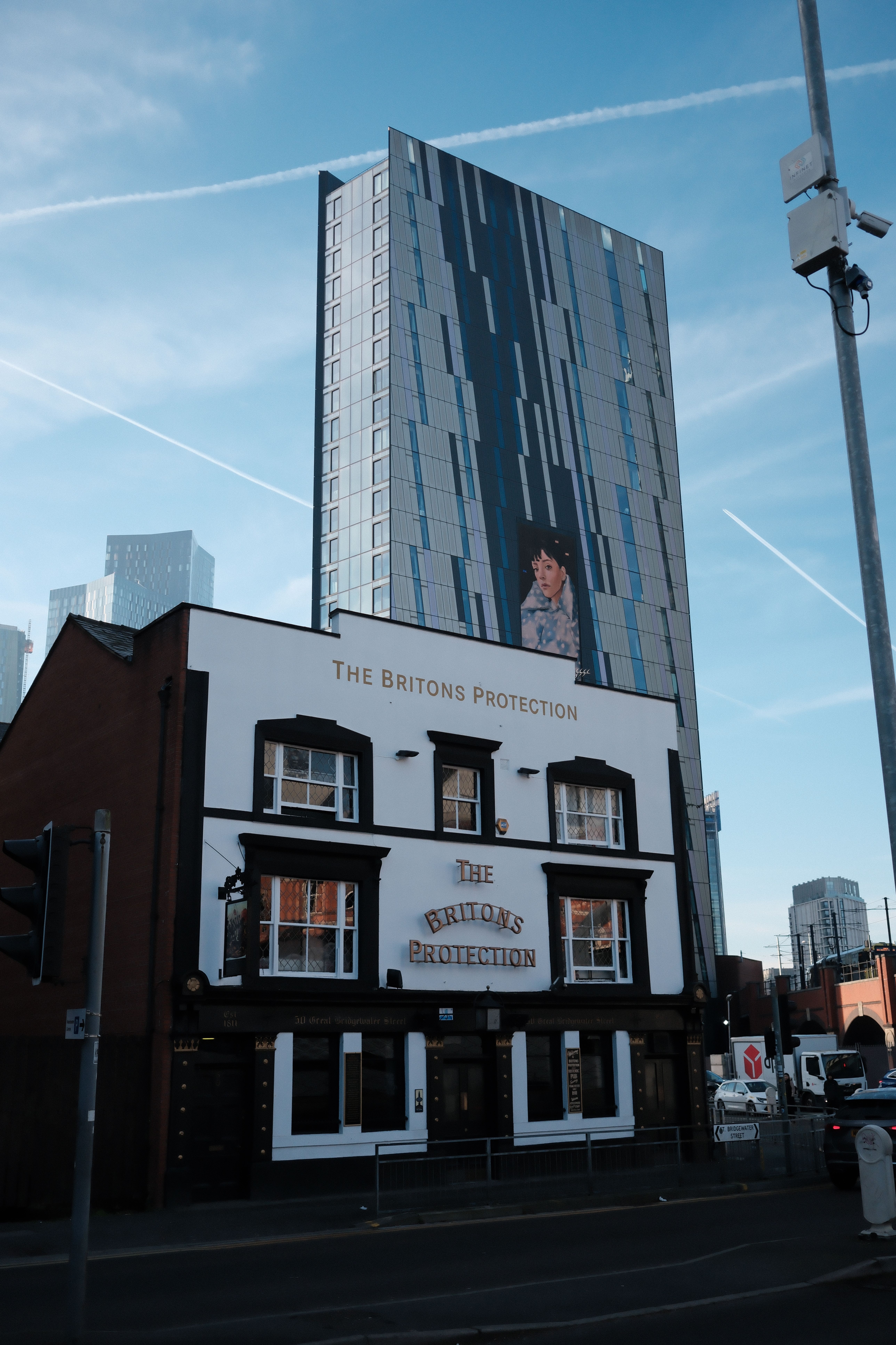 Historic Britons Protection pub beside modern skyscraper under clear sky.