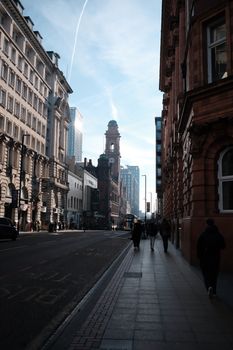 A bustling city street featuring a prominent clock tower amid historic and modern architecture.