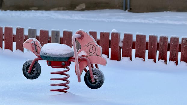 A brightly colored spring rider covered in snow in an empty winter playground.