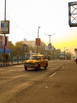 Early morning view of a vintage yellow taxi on a quiet urban street with sunrise glow.