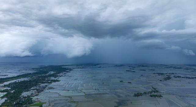 Aerial view of flooded fields in Bangladesh under dramatic storm clouds.
