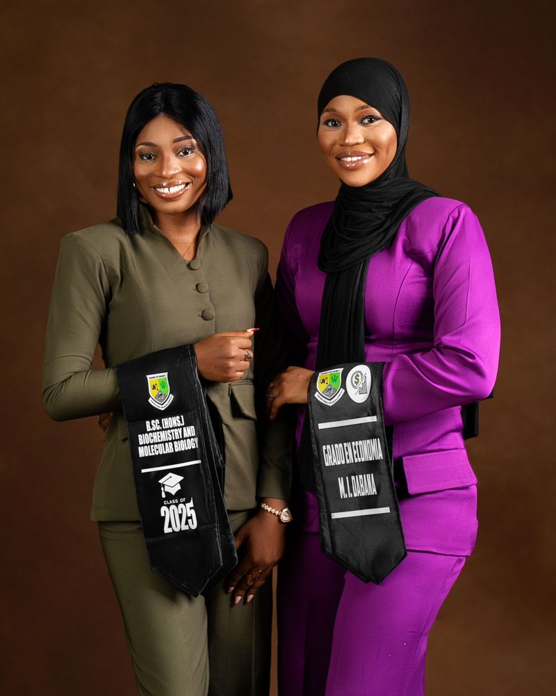 Two smiling women in graduation attire celebrating their success.