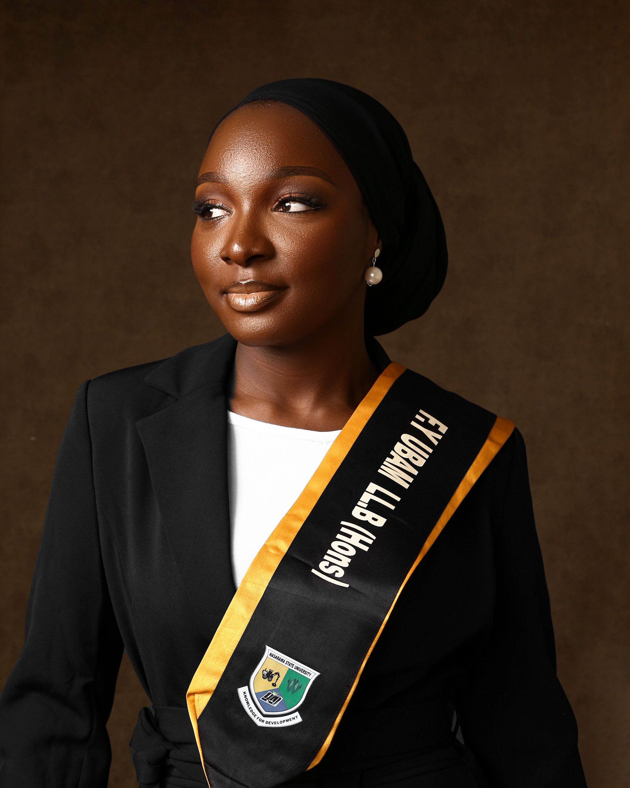 Elegant portrait of a graduating student in academic gown with honors sash.