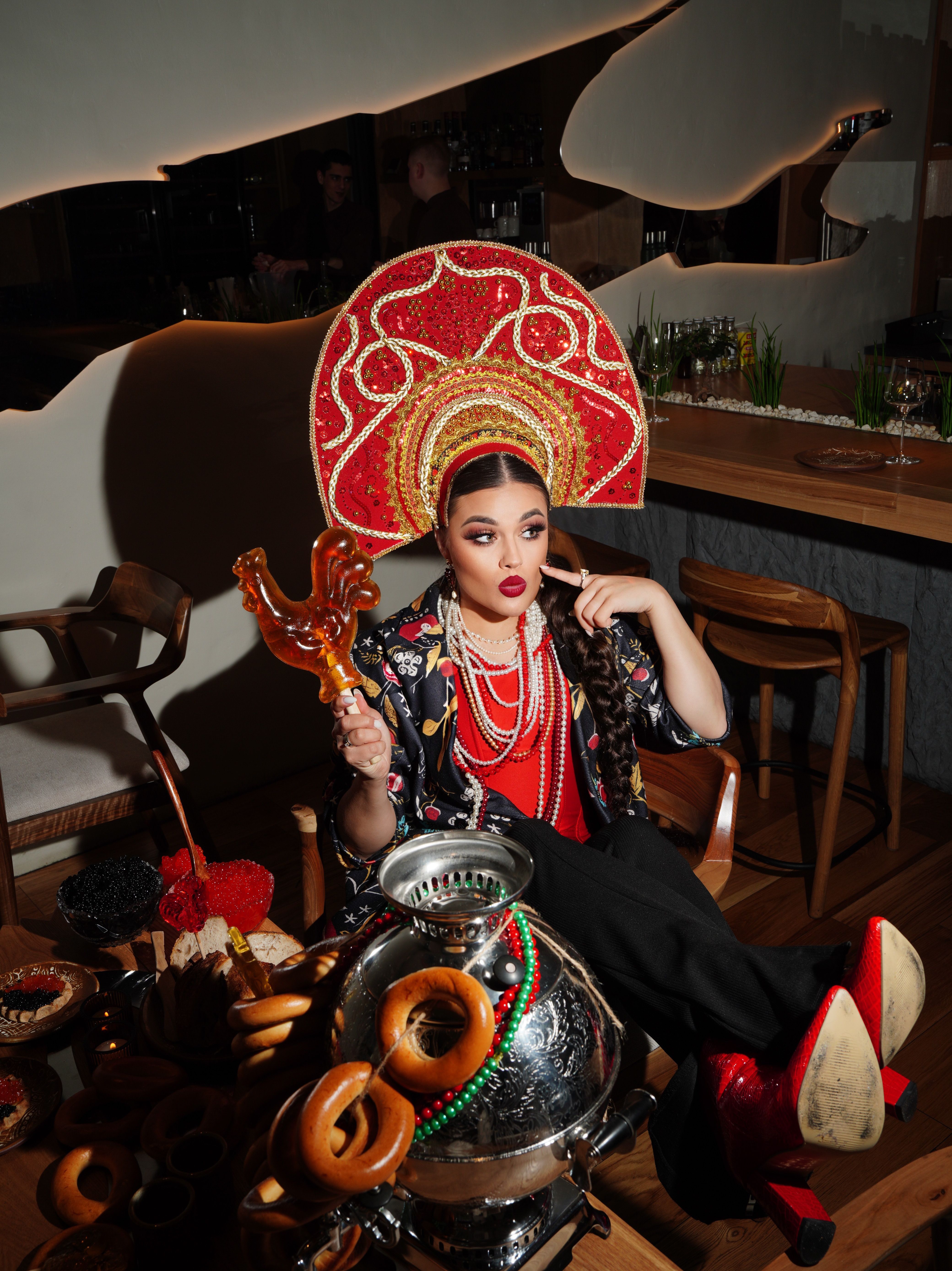 Woman in vibrant Russian attire with a kokoshnik, holding a scepter in a modern setting.