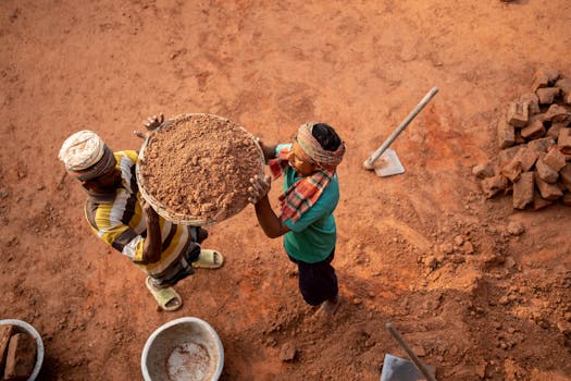 Two men working in a brick field in Dhaka, showcasing hard labor and teamwork.