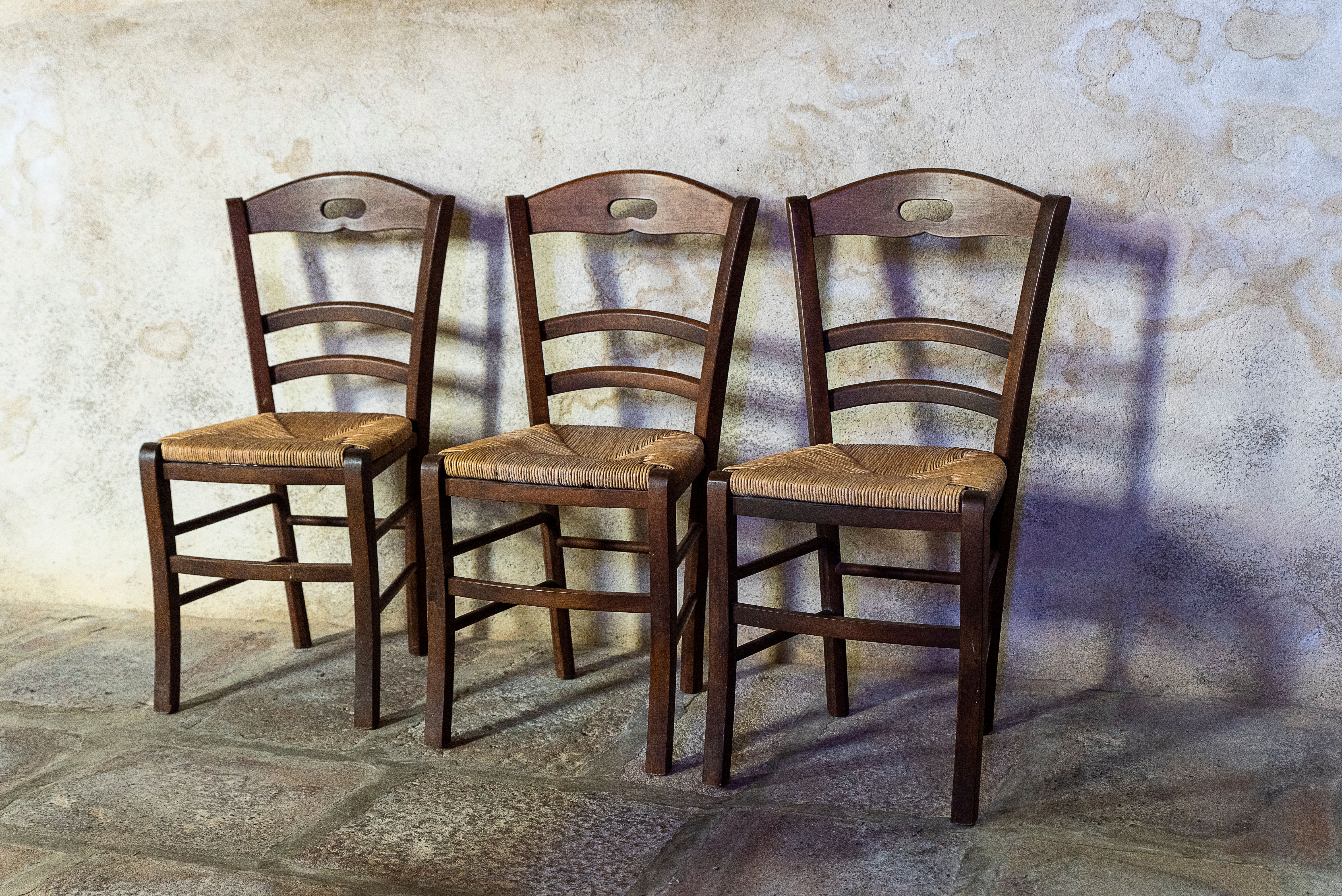 Three Wooden Chairs Against Rustic Wall · Free Stock Photo