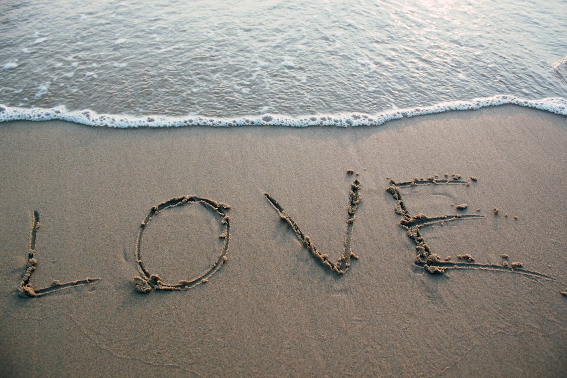Free Brown Sand Love Text on Seashore Stock Photo
