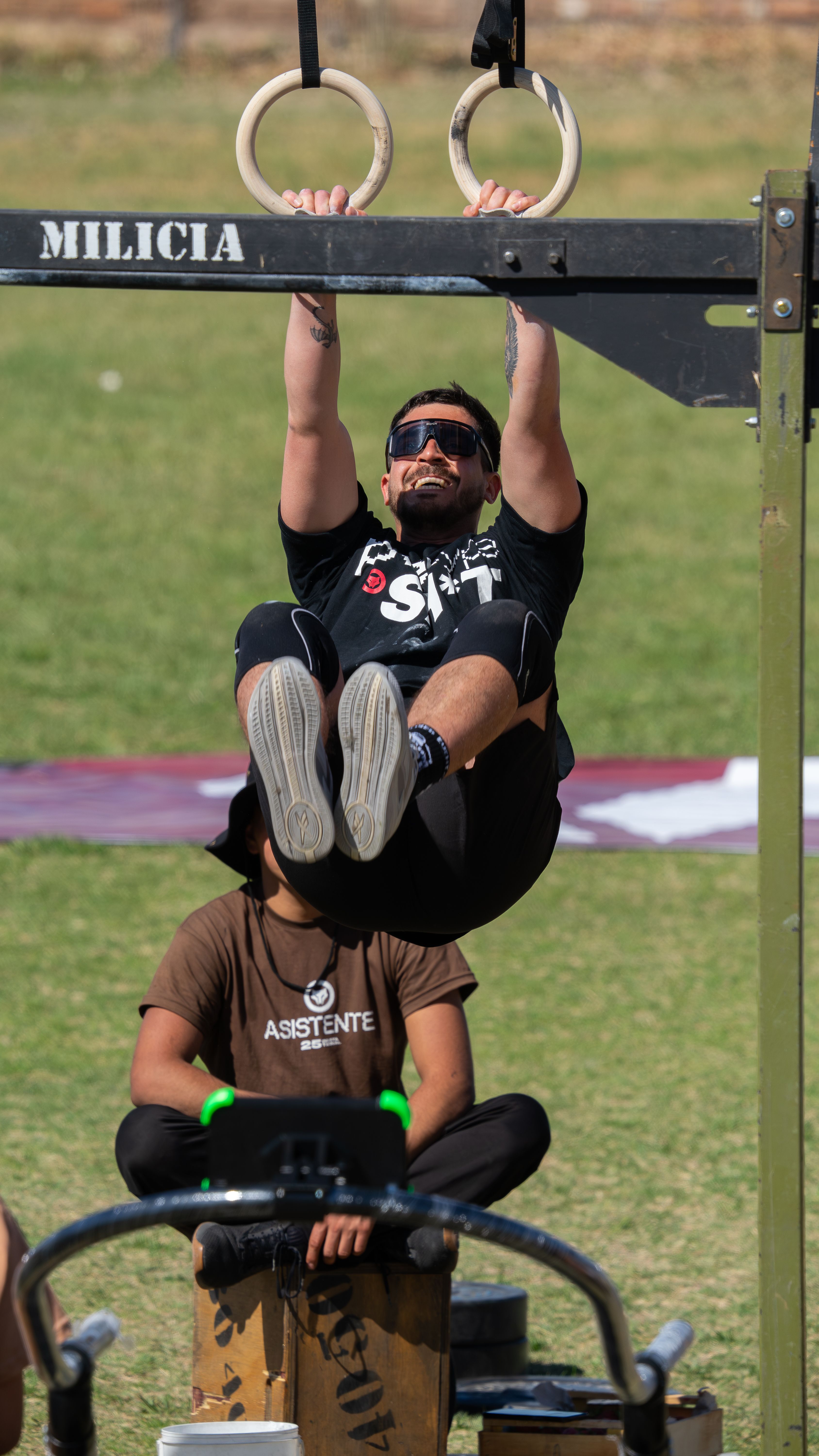 A man exercises on gymnastics rings during an outdoor fitness event.