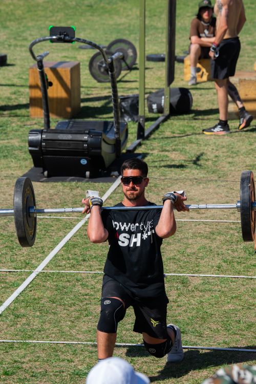 Free A focused athlete performs a barbell lunge during an outdoor fitness event, showcasing strength and balance. Stock Photo