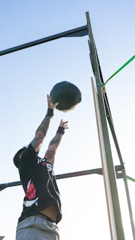 Man throwing a medicine ball into the air during an outdoor fitness session.