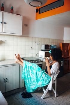 Woman sitting in cozy kitchen enjoying coffee, embodying relaxation and homely comfort.