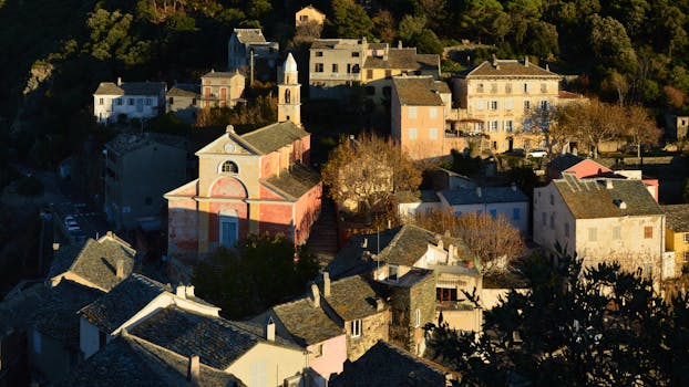 Scenic view of Nonza, Corsica featuring historic buildings and beautiful golden hour lighting.