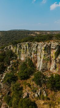 Aerial view of rugged cliffs with lush greenery in Guanajuato, Mexico under a clear blue sky.