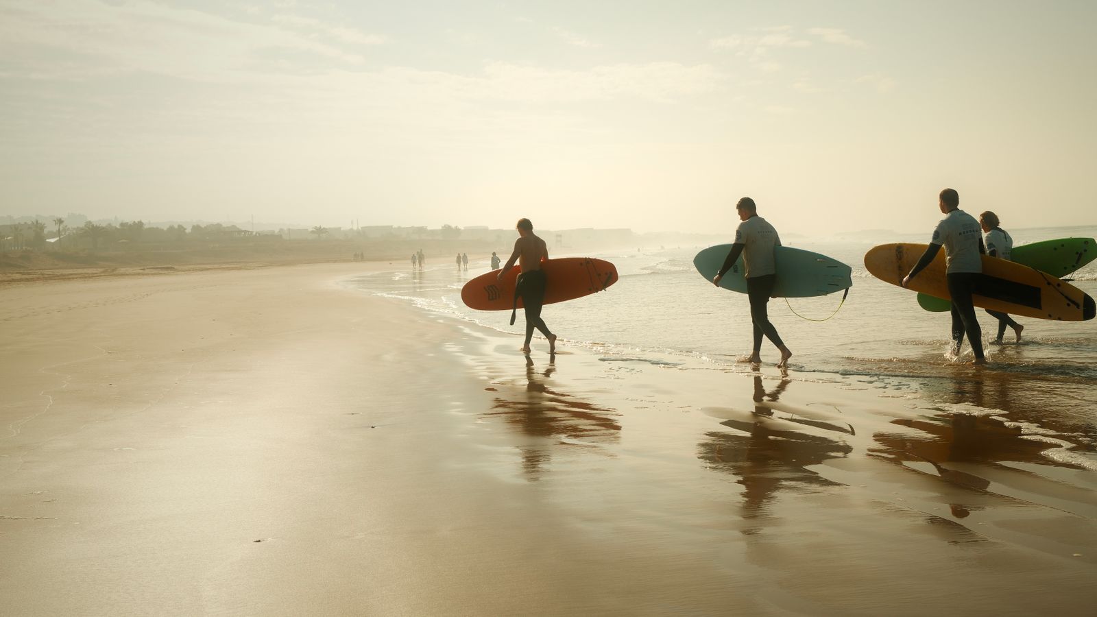 Surfers heading to moroccan waves at sunset