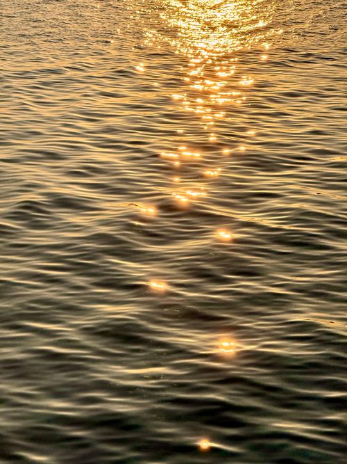 Free Glittering sunlight reflection over ocean water surface during sunset. Stock Photo